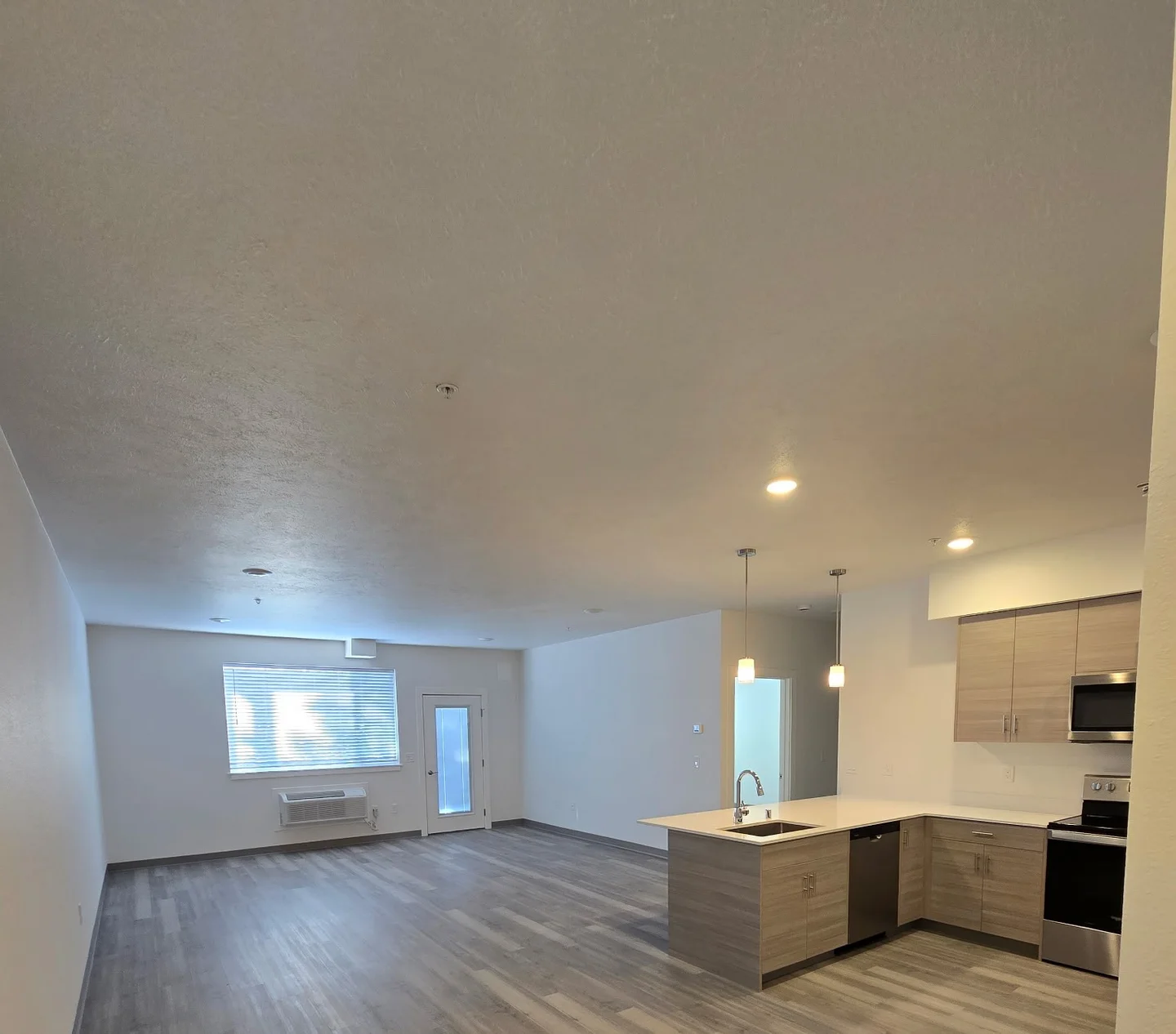 Open living room and kitchen with light walls and a textured ceiling