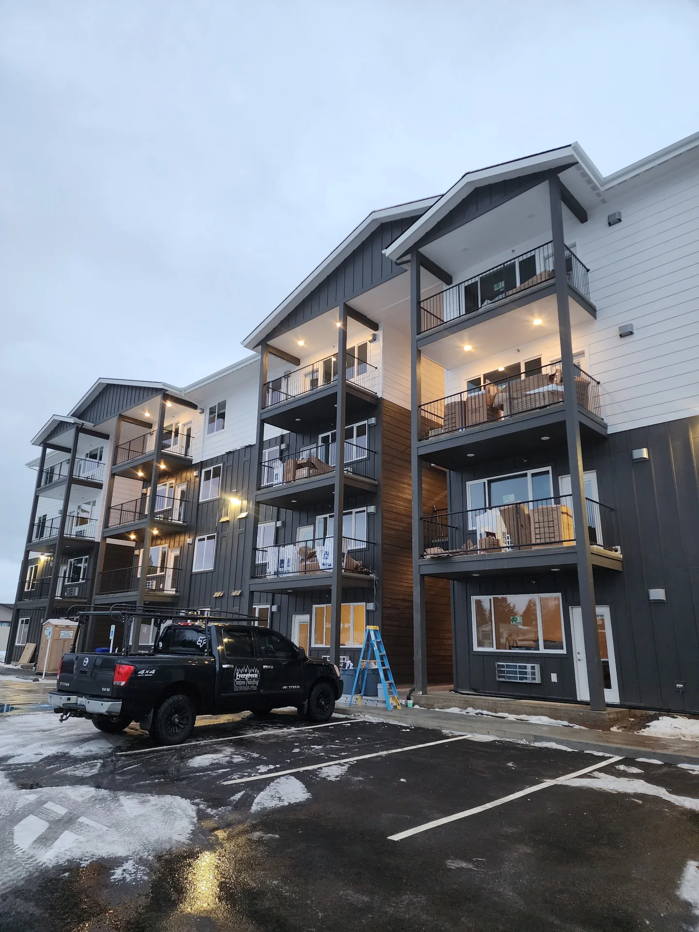 Multi-story building with white siding, dark trim, and balconies