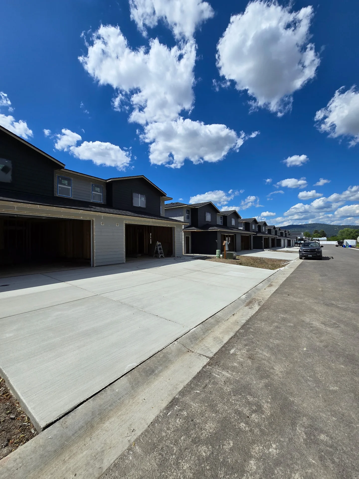 Row of homes with dark upper siding and light garage surrounds